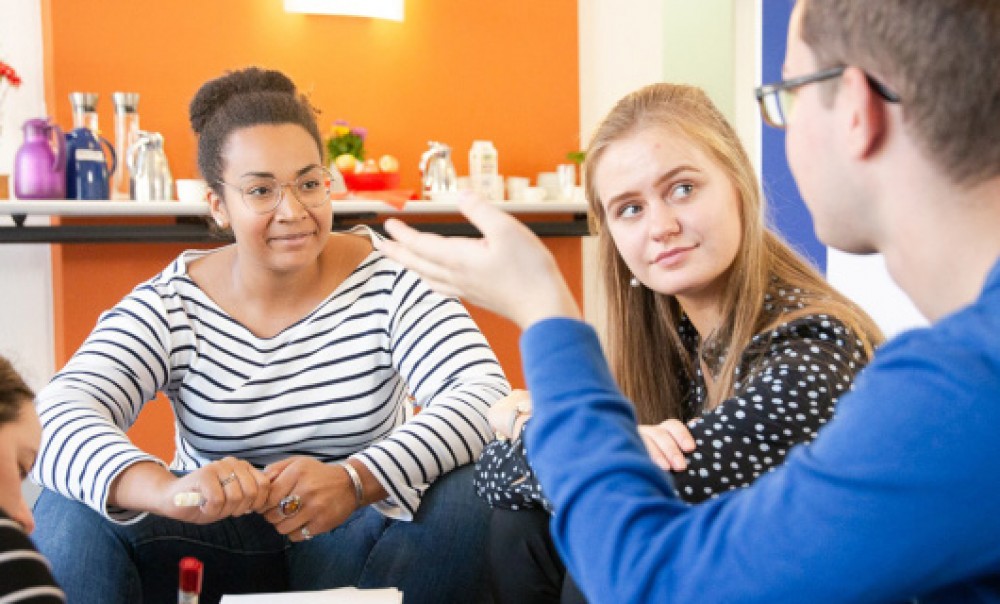 Zwei Frauen und ein Mann diskutieren miteinander