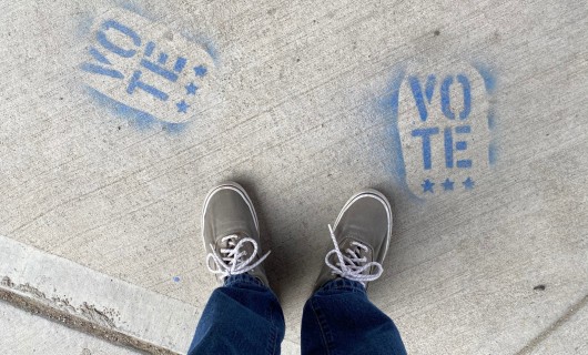 Blaue Sneakers stehen auf dem Boden neben dem Schriftzug vote.