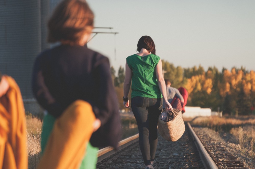 Junge Menschen gehen auf Bahnschienen und sind von hinten zu sehen.