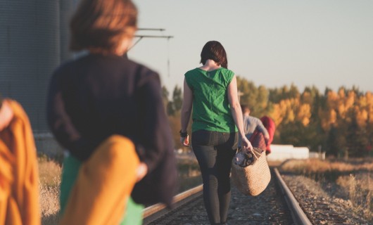 Junge Menschen gehen auf Bahnschienen und sind von hinten zu sehen.